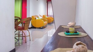 Un interior moderno con una mesa de madera larga, sillas de mimbre y asientos de color naranja brillante.