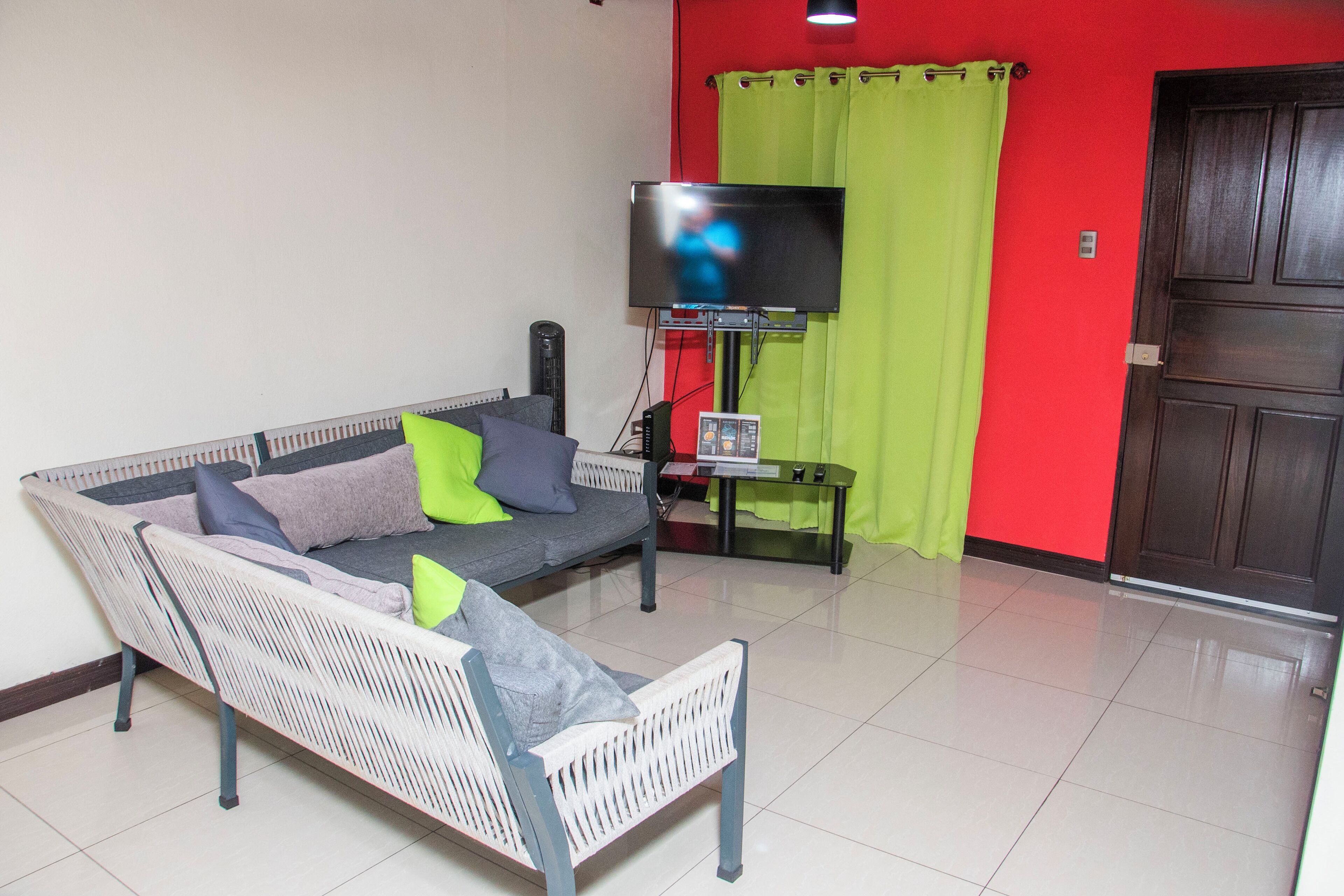 A living room with a sofa, a television, and a door.