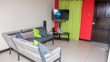 A living room with a sofa, a television, and a door.