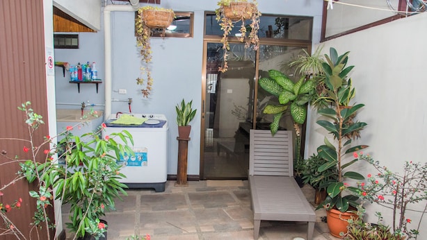 Un pequeño patio con una banca, plantas en macetas y un refrigerador.