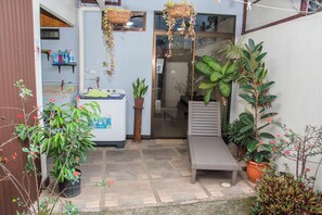 A small patio area with a bench, potted plants, and a refrigerator. - Aloj Entero 1km Juan Santamaría Airport (San Antonio)