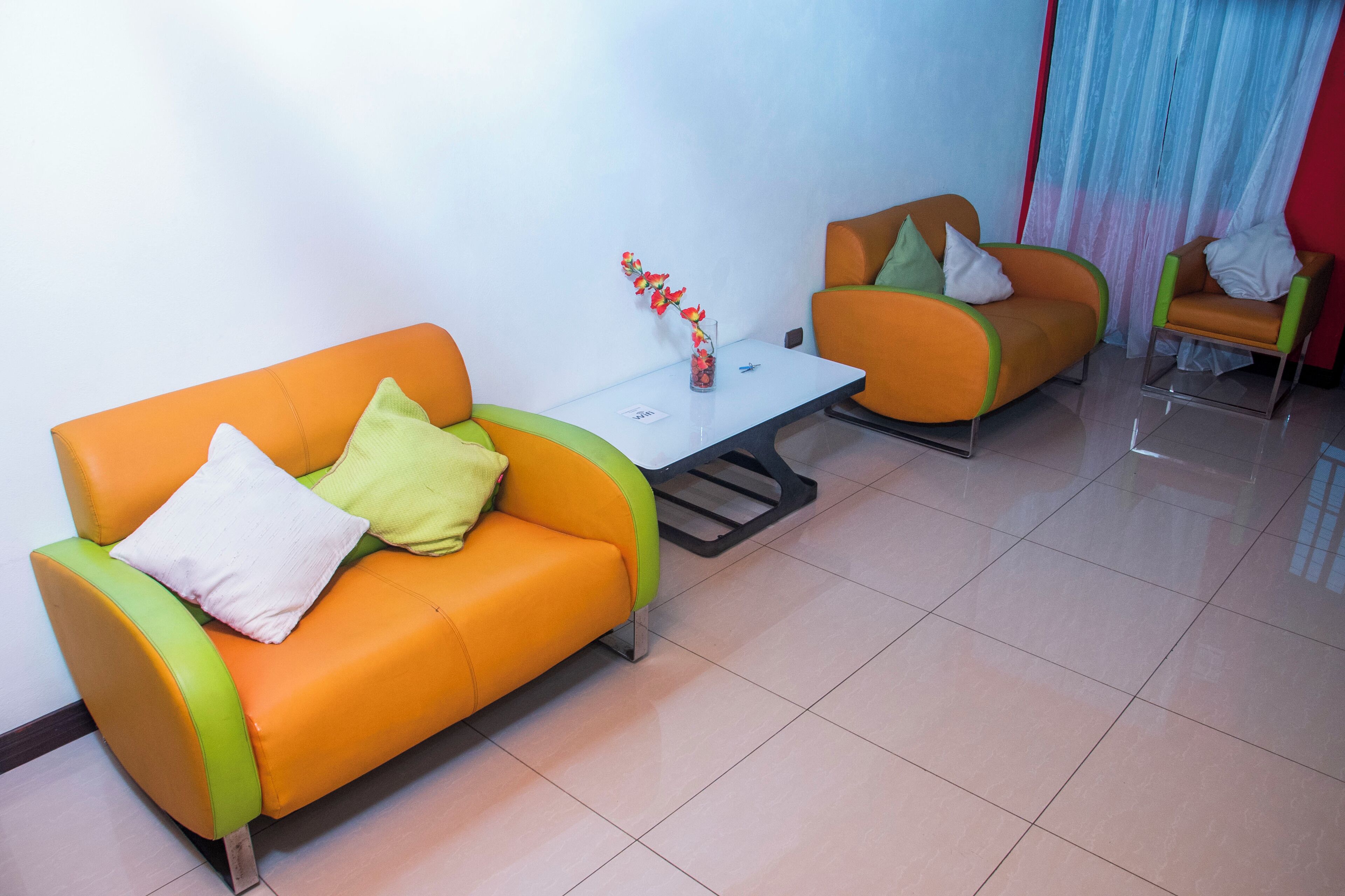 Un salón moderno con dos sofás naranjas, una mesita blanca y una mesa de centro de vidrio.