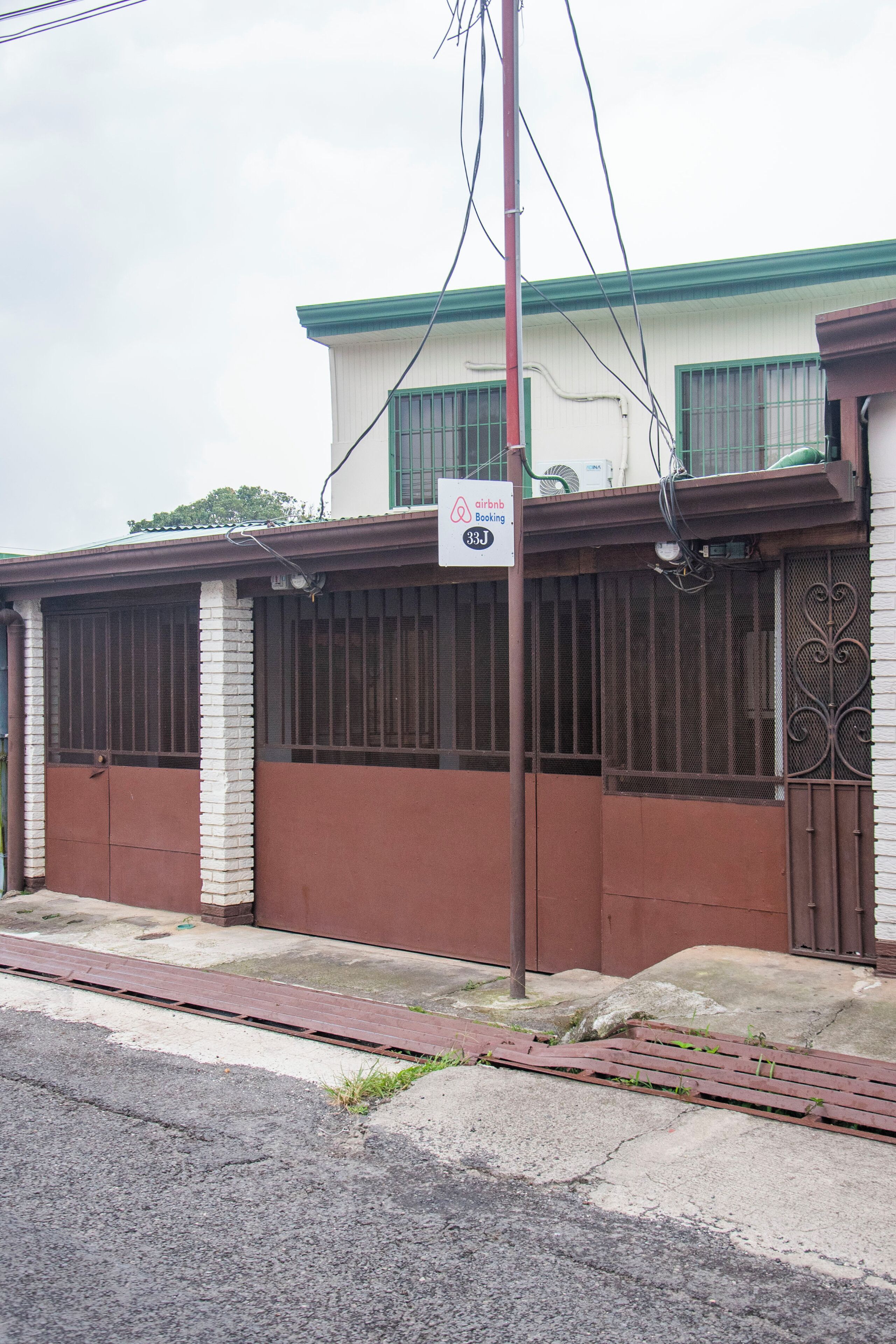 Um edifício com placa da Airbnb, entrada com portão e varanda visível.