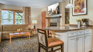 A living room with a sofa, a coffee table, and a chair. There is a kitchen area with a counter and cabinets. - Bluegreen Vacations Streamside at Vail, an Ascend Collection Resort (Vail)