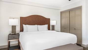 Ein Hotelzimmer mit einem großen Bett, zwei Nachttischen mit Lampen, einem Kleiderschrank und einem Deckenventilator.