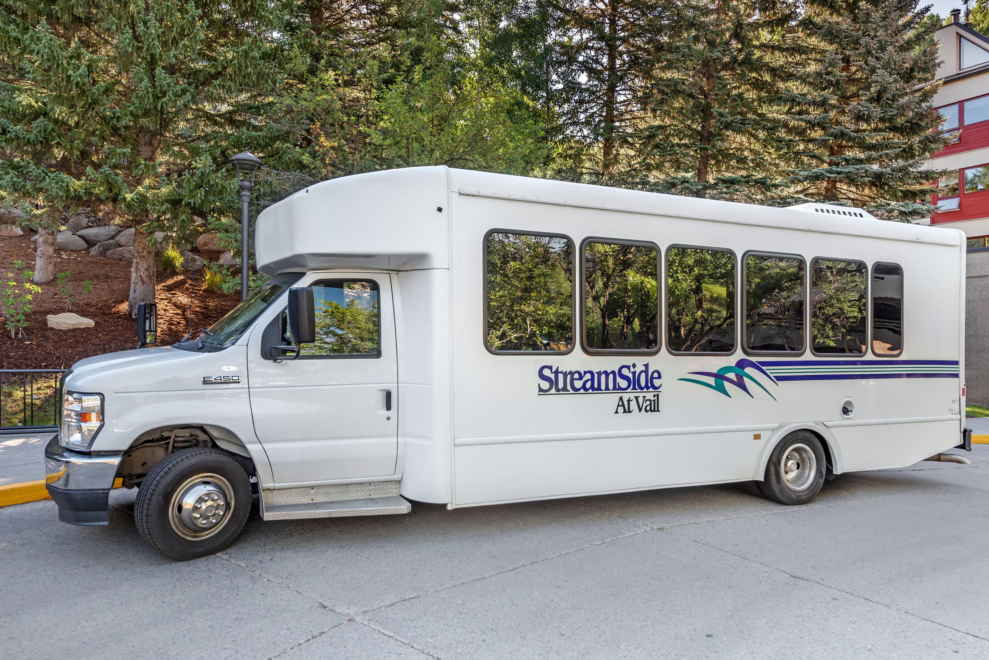 En vit buss med texten ”StreamSide At Vail” på sidan står parkerad på en gata.
