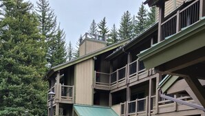 A multi-story building with a stone facade, balconies, and a green awning. - Bluegreen Vacations Streamside at Vail, an Ascend Collection Resort (Vail)