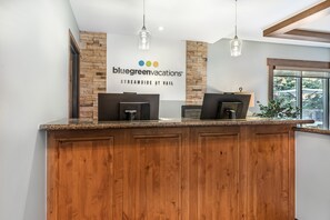 A reception desk with a stone wall backdrop, a sign for Bluegreen Vacations, and a window with a view.
