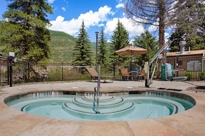 A swimming pool with a fountain, surrounded by a fence, chairs, and an umbrella. - Bluegreen Vacations Streamside at Vail, an Ascend Collection Resort (Vail)