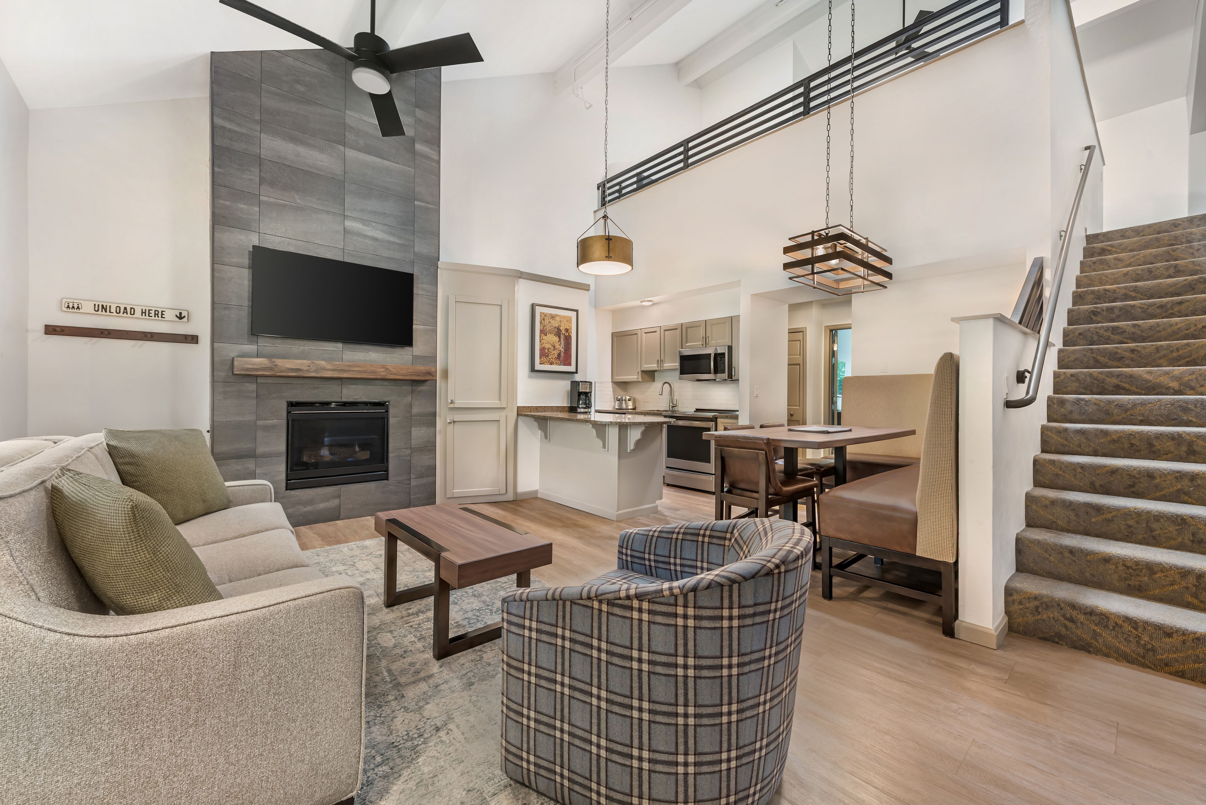 A spacious living area with a fireplace, a dining table, and a staircase.