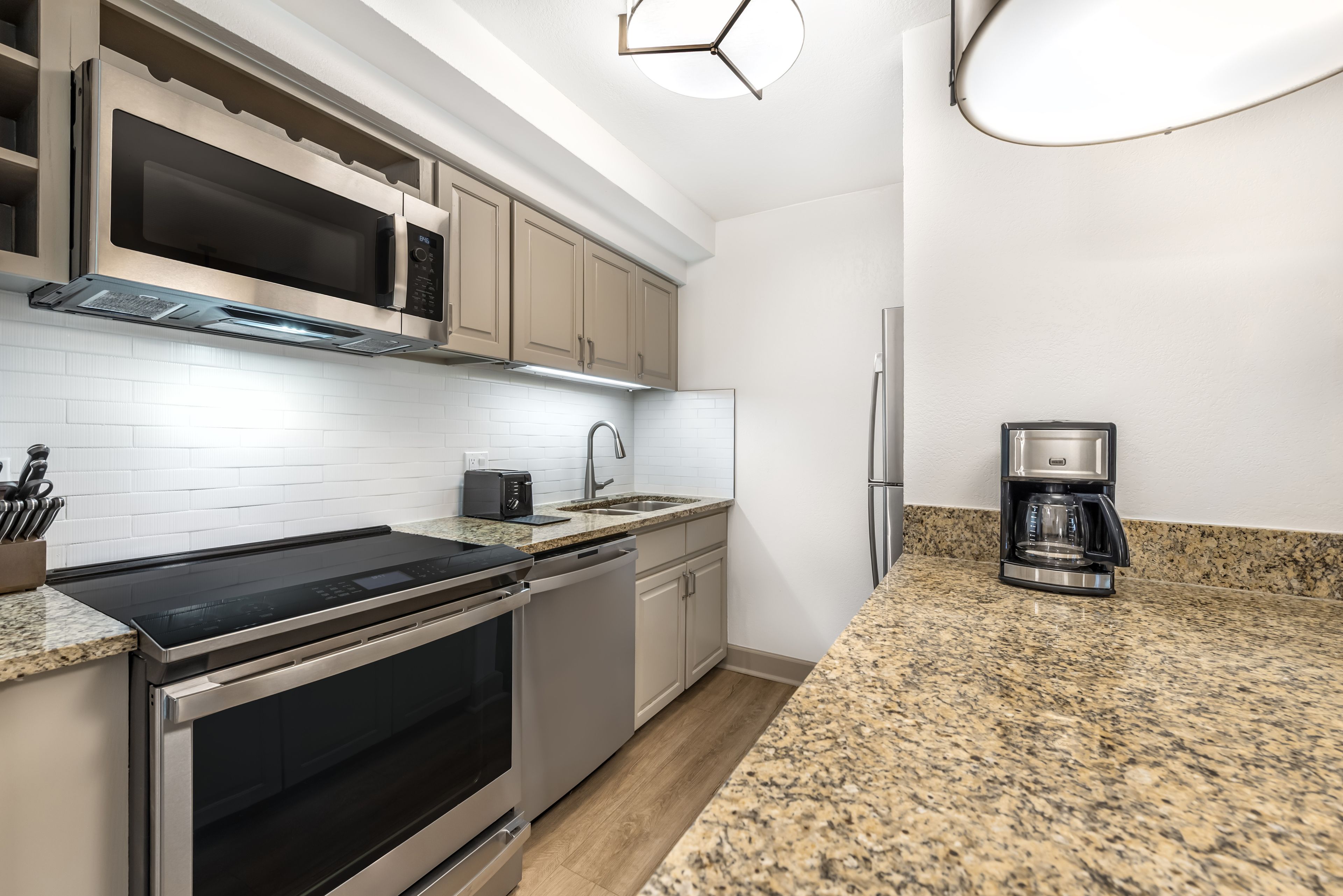 A modern kitchen with stainless steel appliances, a granite countertop, and white subway tiles.