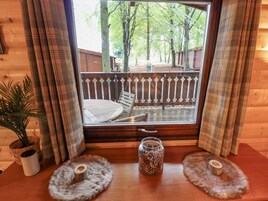 Una cabaña de madera con una ventana que da a una terraza cercada.