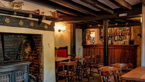 A cozy bar area with wooden furniture, a brick wall, and a fireplace. - Cottage in Area of Outstanding Natural Beauty (Didcot)