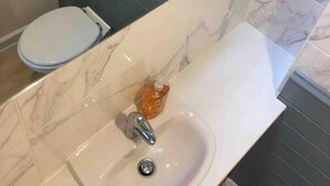 Een badkamer met een wit wastafel, een spiegel en een toilet.