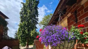 A brick house with a hanging flower basket and a wooden table with chairs. - Cottage in Area of Outstanding Natural Beauty (Didcot)