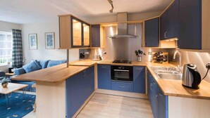 Een kleine keuken met blauwe kastjes, een houten aanrechtblad en een ingebouwde oven.