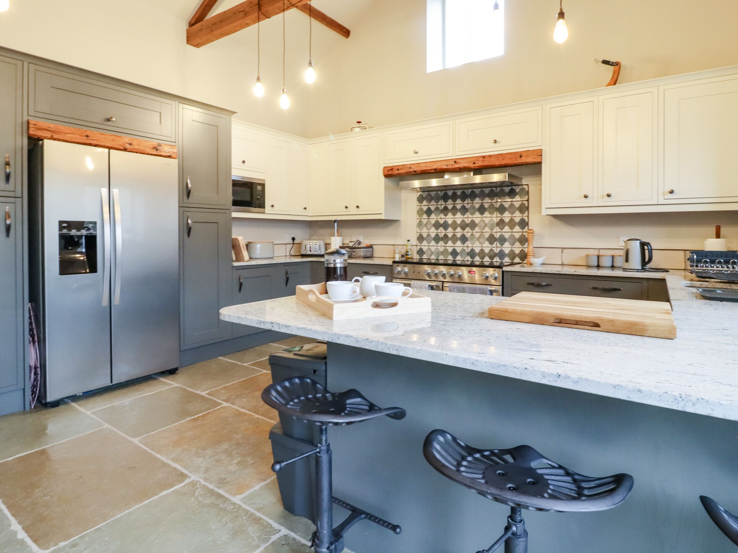 A modern kitchen with a large island, stainless steel appliances, and a unique backsplash.
