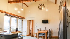 Un'ampia cucina con travi in legno, un'area pranzo con tavolo e sedie, e un'ampia finestra che offre luce naturale.