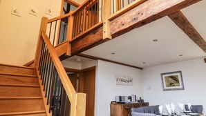 Una scala in legno con ringhiera, una sala da pranzo con tavolo imbandito per quattro persone e una parete decorata con opere d'arte.