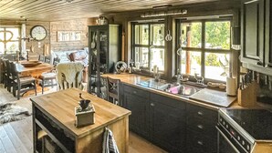 Una cocina rústica con mostradores de madera, un lavamanos y una zona de comedor con una mesa y sillas.