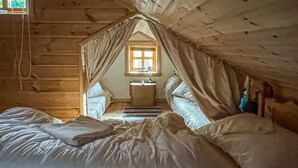 Un dormitorio acogedor en el ático, con cama, mesita de noche y ventana.