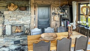 Un comedor rústico con chimenea de piedra, mesa y sillas de madera.