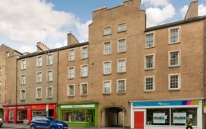 A multi-story building with a brick facade, several ground-floor shops, and a visible entrance. - University and Central Edinburgh (Newington)