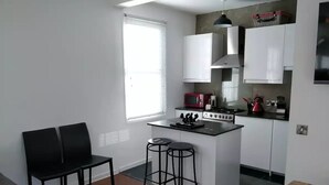A compact kitchen with a central island, bar stools, and a dining area with a bench.