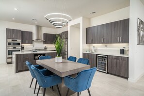 Een moderne keuken met donkere kastjes, roestvrijstalen apparatuur en een centraal eiland met blauwe stoelen.