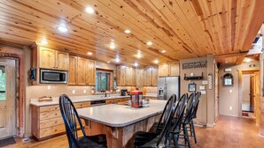 Une cuisine spacieuse avec des meubles en bois, un îlot central doté de chaises et des appareils électroménagers modernes.