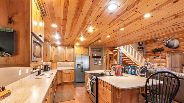 L’intérieur d’une cabane en bois comprend une cuisine équipée de plans de travail en granit, de meubles en bois, d’un réfrigérateur, d’une cuisinière et d’un évier.