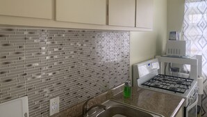 A kitchen with a tiled backsplash, a stainless steel sink, a gas stove, and a microwave. - Elana's WhiteHouse. #3 Anasco PR. (Añasco)