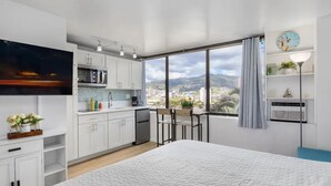 A modern hotel room with a large bed, a kitchenette, a dining area, and a city view. - King Bed/Renovated/Canal& Mountain View/Walk Beach (Honolulu)