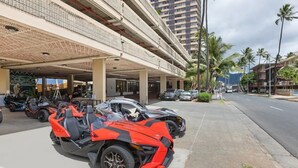 A multi-story parking structure with several ATVs parked in front. - King Bed/Renovated/Canal& Mountain View/Walk Beach (Honolulu)