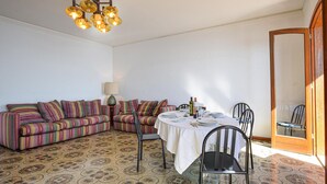 Un comedor con una mesa lista para dos, un sofá a rayas y un suelo estampado.