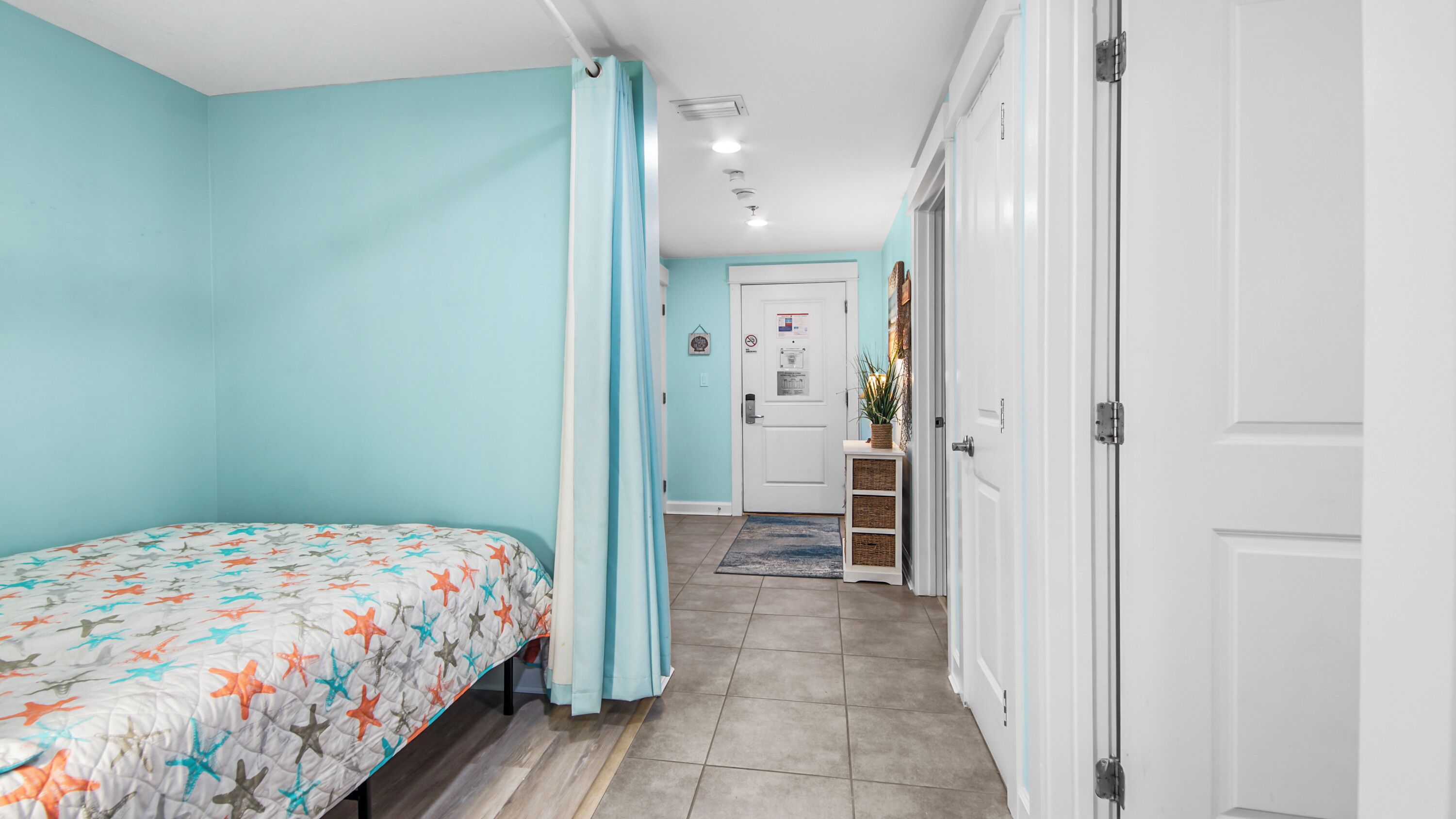 A bedroom with a bed, a door, a hallway, and a bathroom.