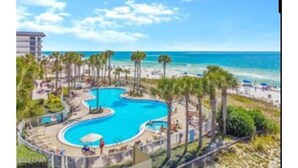Un resort con una piscina grande, palmeras y vista al mar.