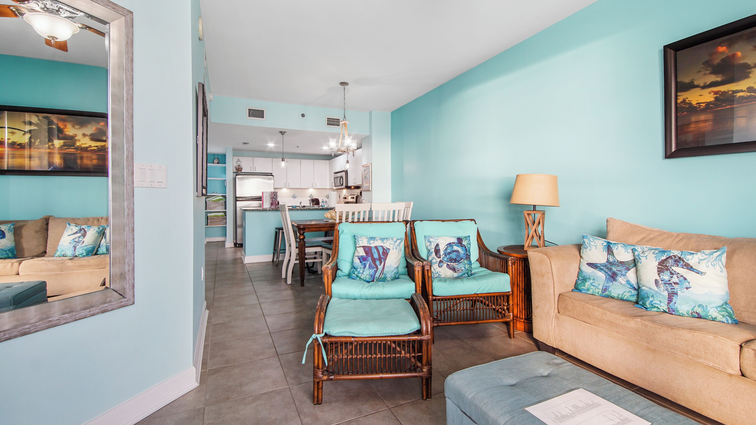 A living room with a sofa, two wicker chairs, a coffee table, and a dining area with a table and chairs.