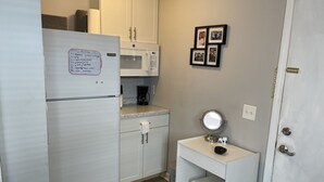 A compact kitchen with a refrigerator, microwave, and coffee maker. There's a small vanity with a mirror and toiletries. - Small Efficiency near Surfside Beach Pier (Surfside Beach)