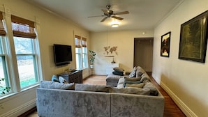 A spacious living room with a large sectional sofa, a ceiling fan, a flat-screen TV, and a world map on the wall.