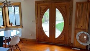 A room with a wooden door, a round table, and a ceiling fan.