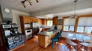 A modern kitchen with wooden cabinets, stainless steel appliances, and a central island with bar stools.