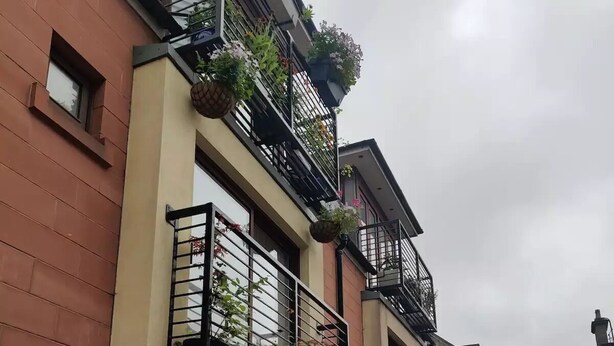 Una hilera de casas escalonadas con balcones, algunos con plantas colgantes.