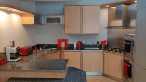 Una cocina moderna con encimeras de granito, electrodomésticos de acero inoxidable y armarios de madera.