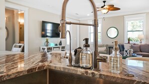 Una cocina con grifo de acero inoxidable, encimera de mármol y una botella de jabón de manos.