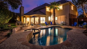 Una casa con piscina, arredi da esterno e un patio ben illuminato.