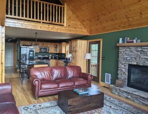 Ein gemütliches Wohnzimmer mit Ledersofa, Couchtisch und Kamin aus Stein.