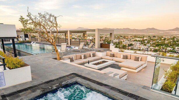 A rooftop pool area with a hot tub, outdoor seating, and a view of the cityscape. - Living in the Heart of Cabos (Cabo San Lucas)