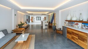 A modern hotel lobby with a sofa, coffee table, and potted plants. - Living in the Heart of Cabos (Cabo San Lucas)