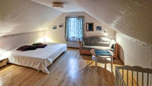 A cozy attic bedroom with a bed, a sofa, and a small table. - Beautiful home in Vena with WiFi (Vena)